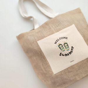 BOLSO YUTE WELCOME SUMMER COLOCADO SOBRE FONDO GRIS