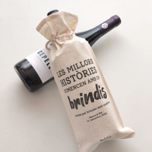 BOLSA PARA VINO BRINDIS EN CATALÁN COLOCADA SOBRE BOTELLA DE VINO